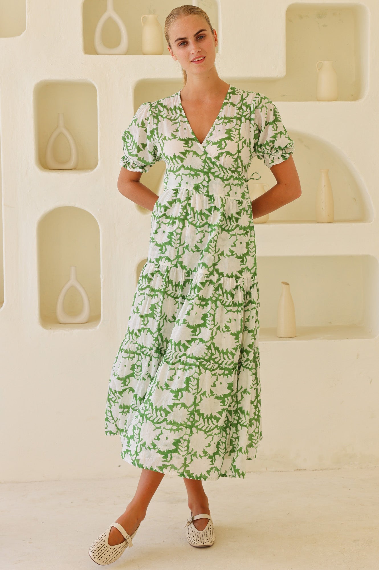 White midi dress with green botanical print, V-neckline, short puff sleeves, and tiered skirt.
