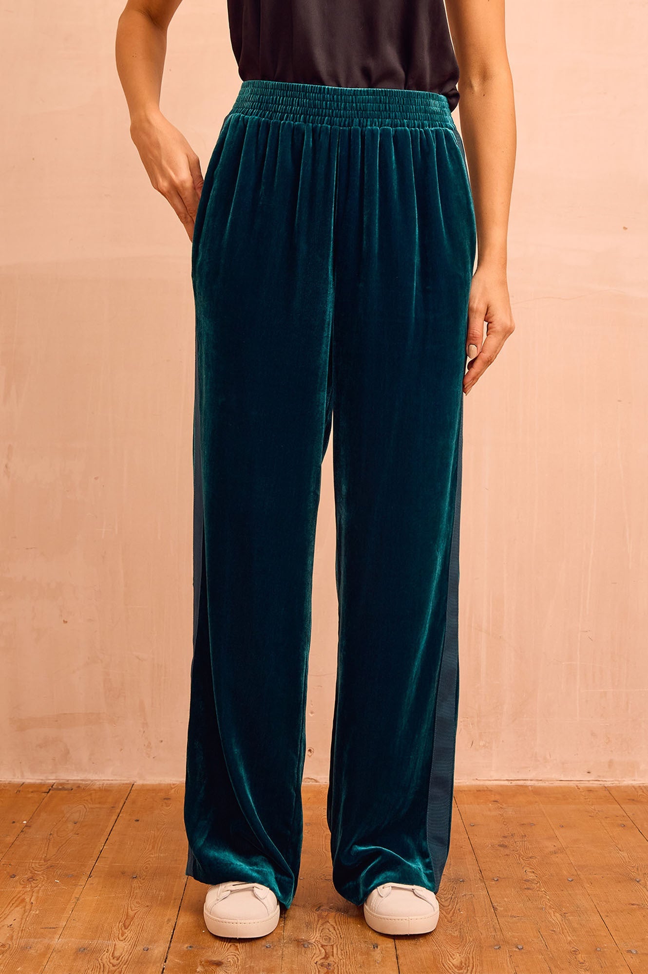 Deep teal velvet wide-leg trousers with elasticated waistband, relaxed fit, and full-length silhouette.
