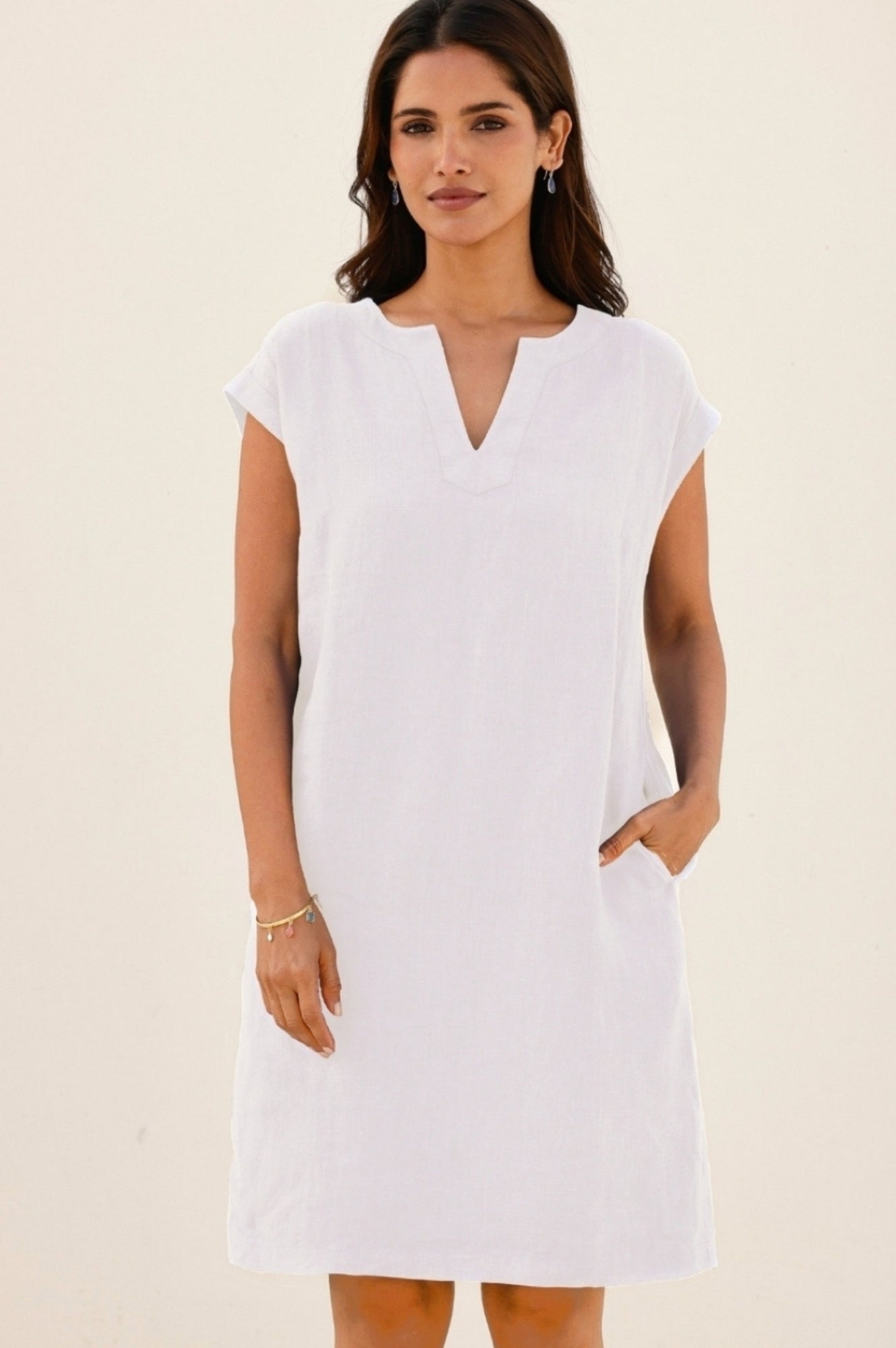 White linen shift dress with short sleeves and a notch neckline.