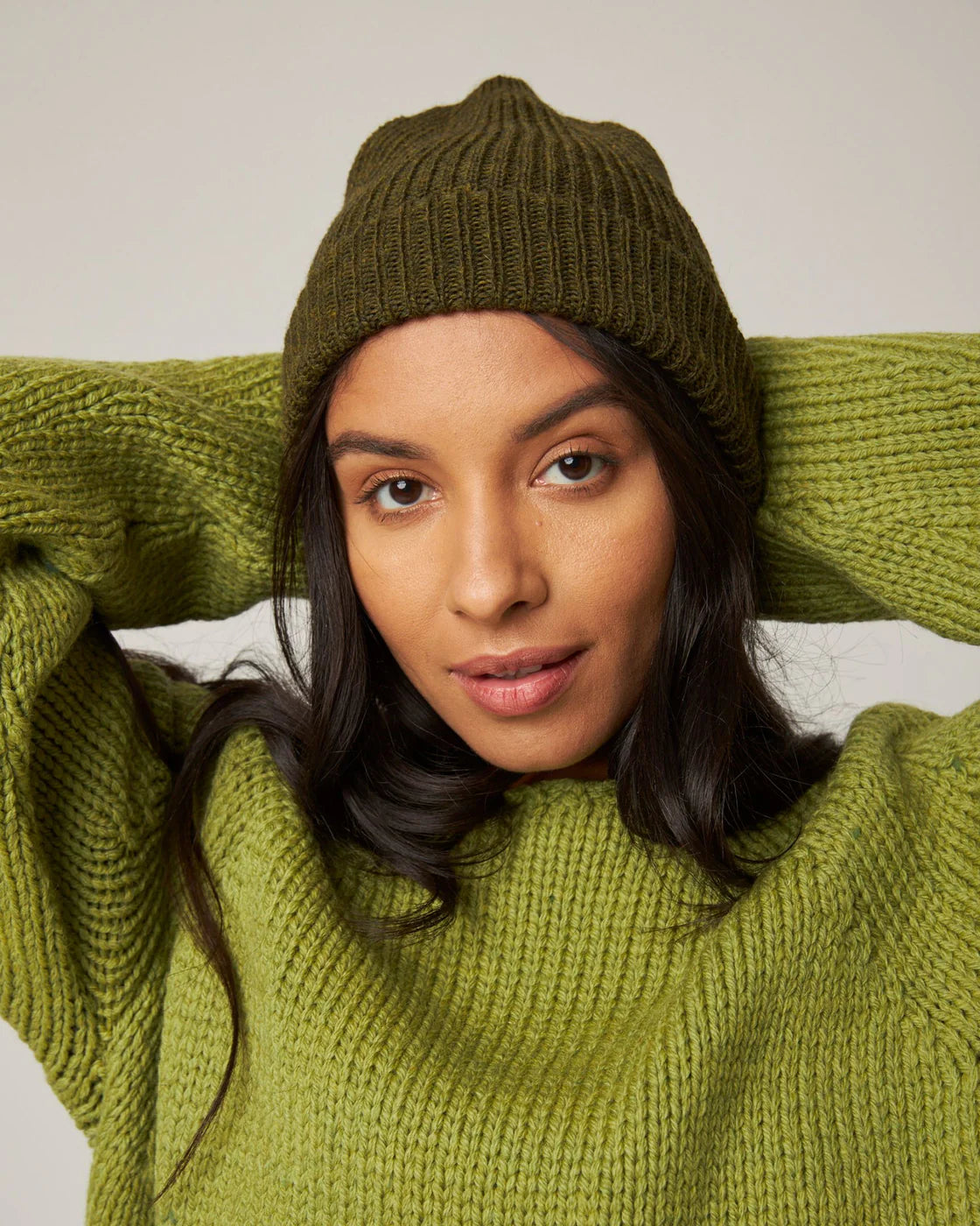 Model wears an olive green merino wool ribbed knit beanie by Peregrine Clothing, filtered for the Soft Autumn, Warm Autumn, and Deep Autumn colour seasons by Shop My Palette.