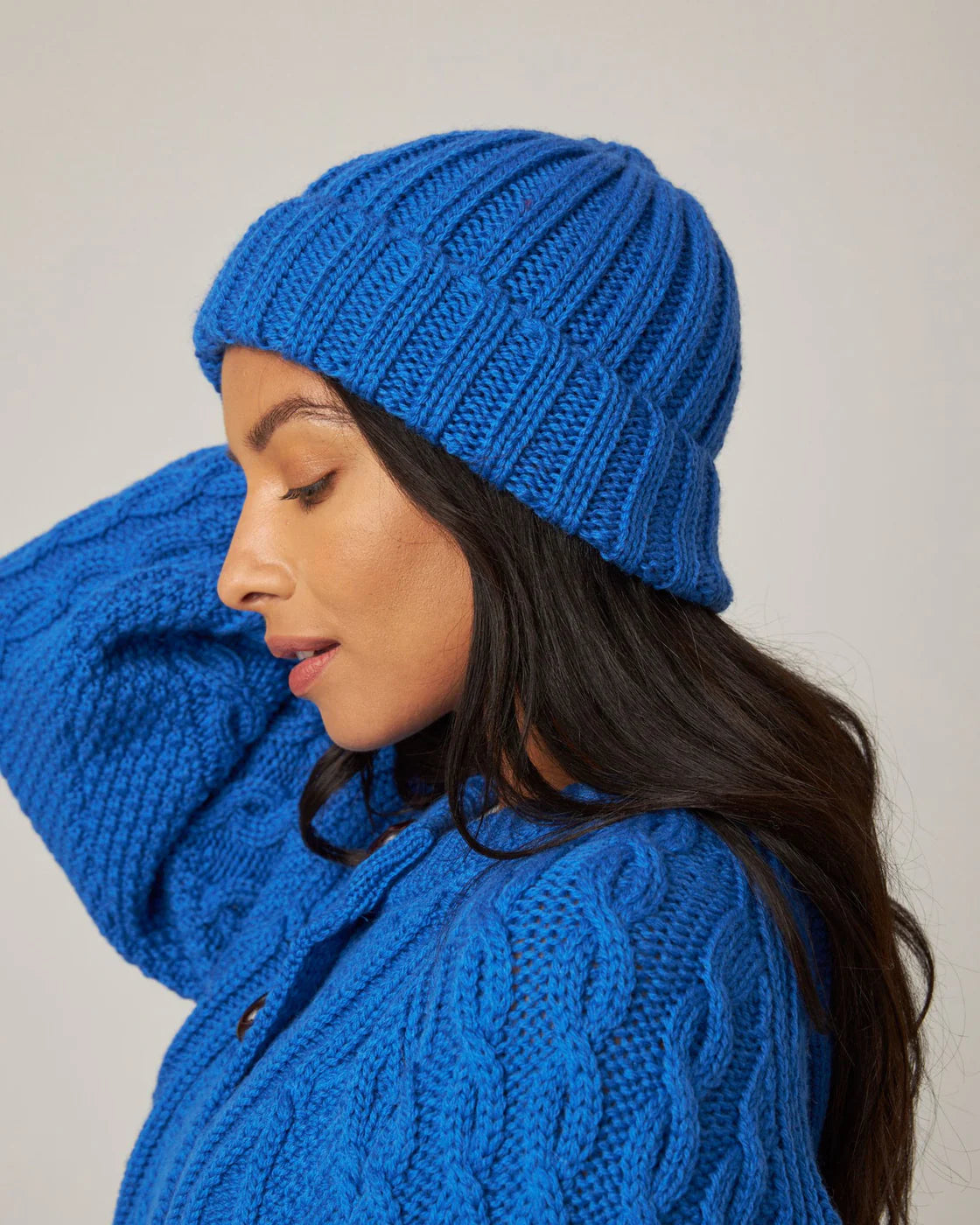 Model wears bright cobalt blue knitted merino wool beanie hat by Peregrine Clothing, filtered for the Clear Spring, Clear Winter, and Cool Winter colour season by Shop My Palette.