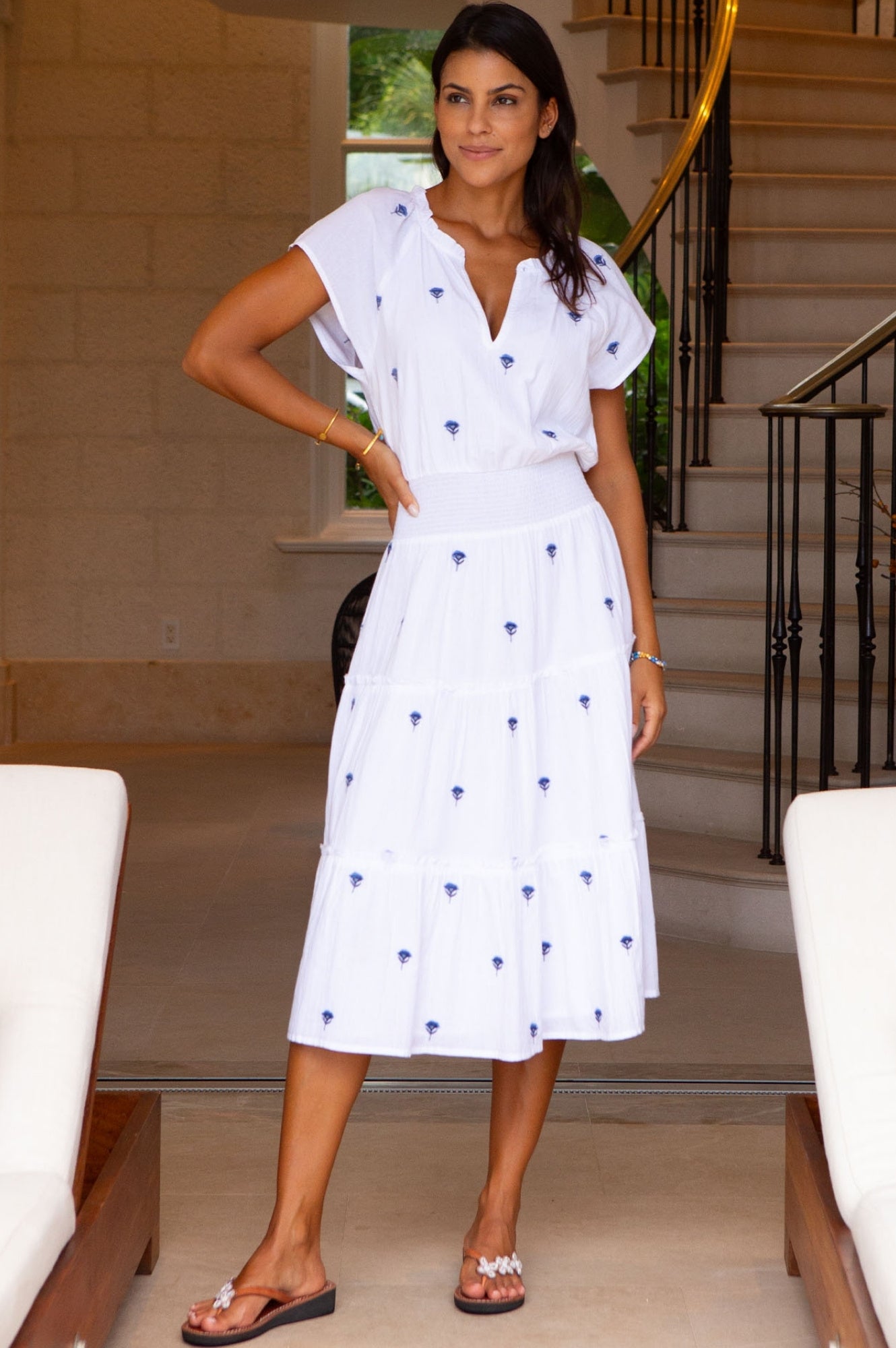 White midi dress with blue embroidered detail, V-neckline, short sleeves, and tiered skirt.