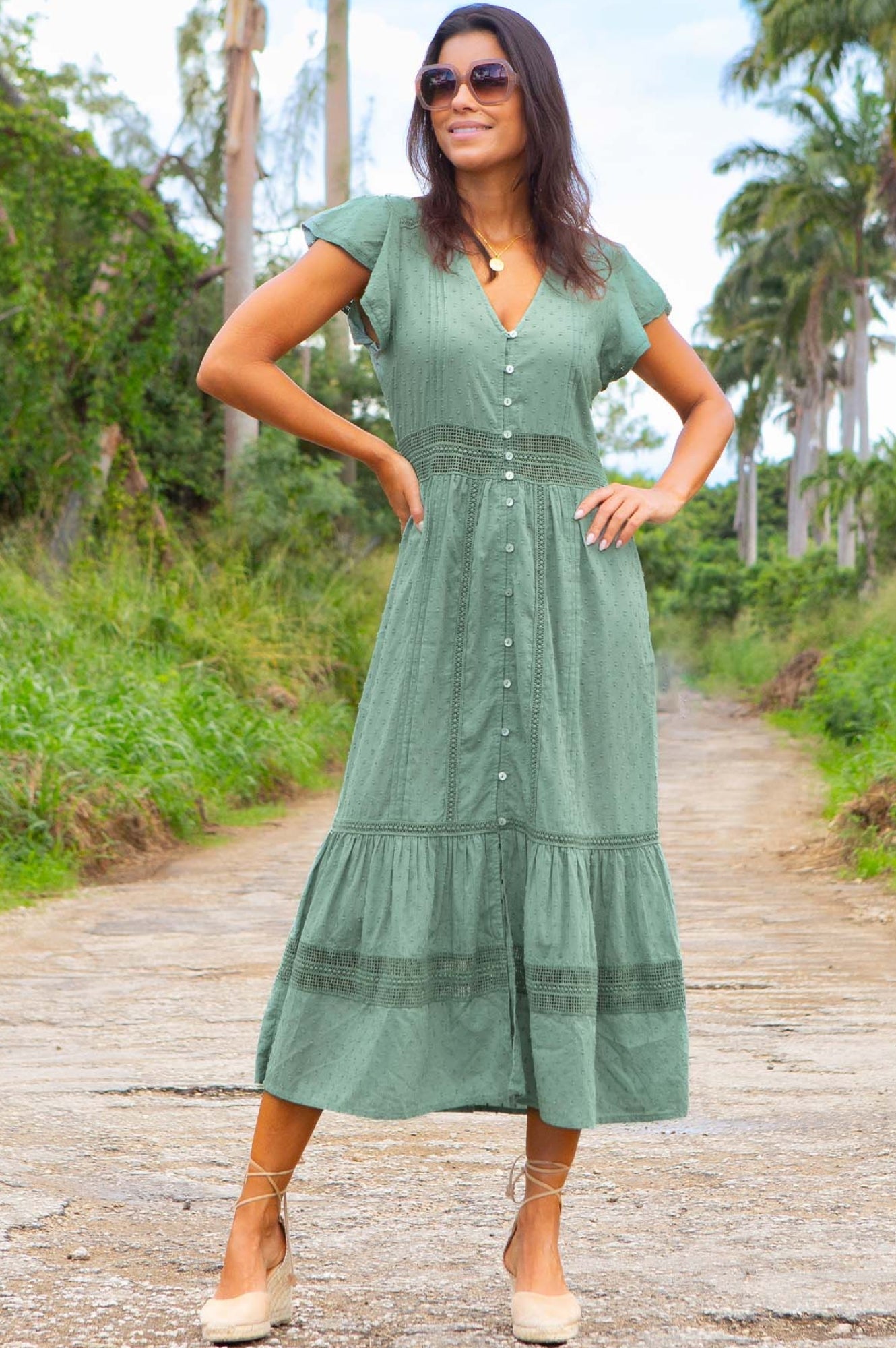 Sage green midi dress with short sleeves, V-neckline, button front, and tiered skirt with textured fabric detail.