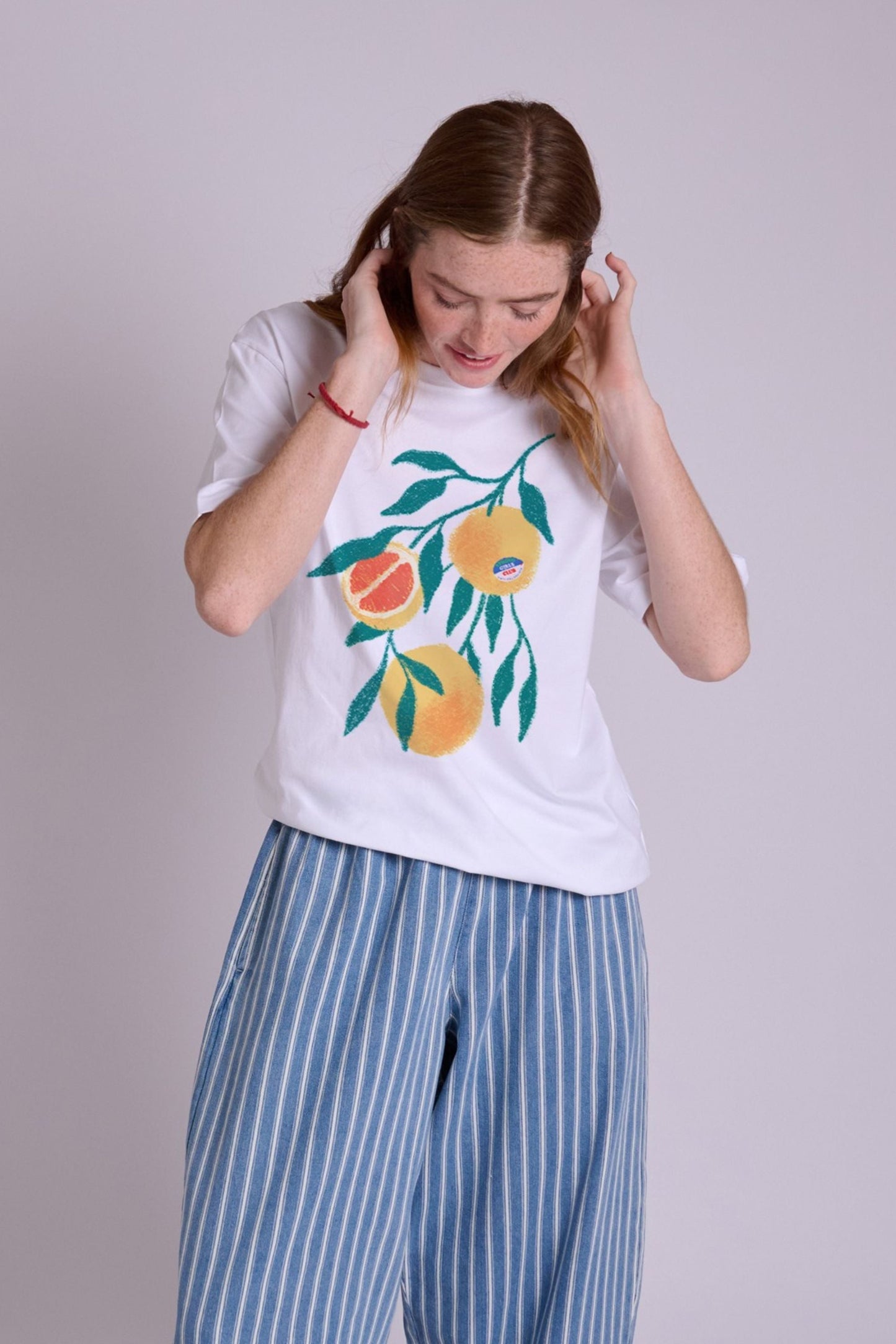 White cotton T-shirt with short sleeves and embroidered orange and green citrus motif on the front.