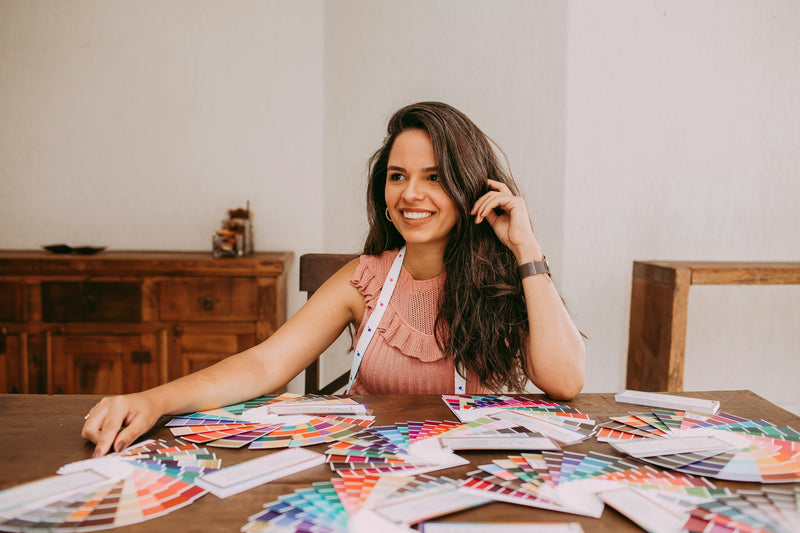 Colour analyst seated at a table covered in colour swatches. Photo by Helena Lopes on Unsplash.