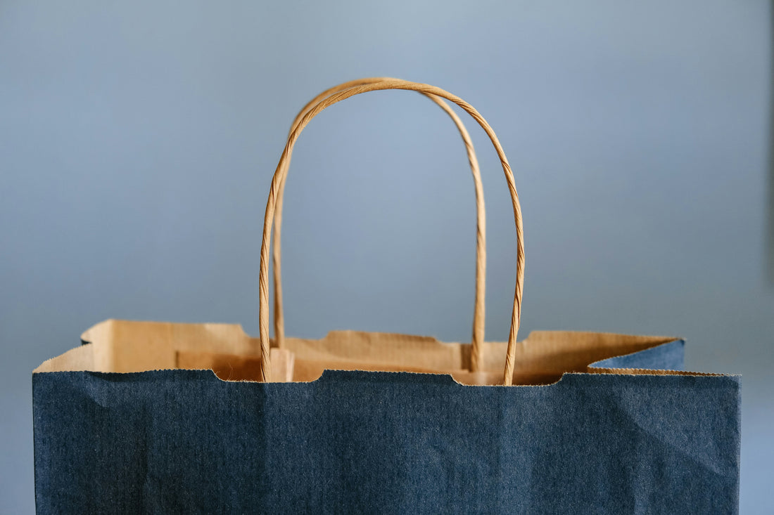 Blue paper shopping bag against pale blue background.
