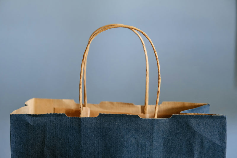 Blue paper shopping bag against pale blue background.