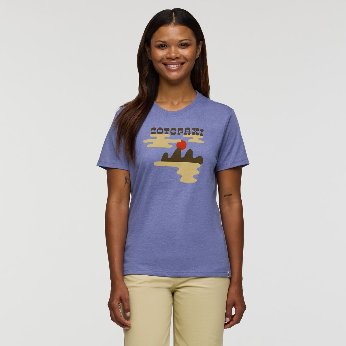 A soft sky blue T-shirt with Cotopaxi and sunrise image graphic on the front in cream, red, and brown.