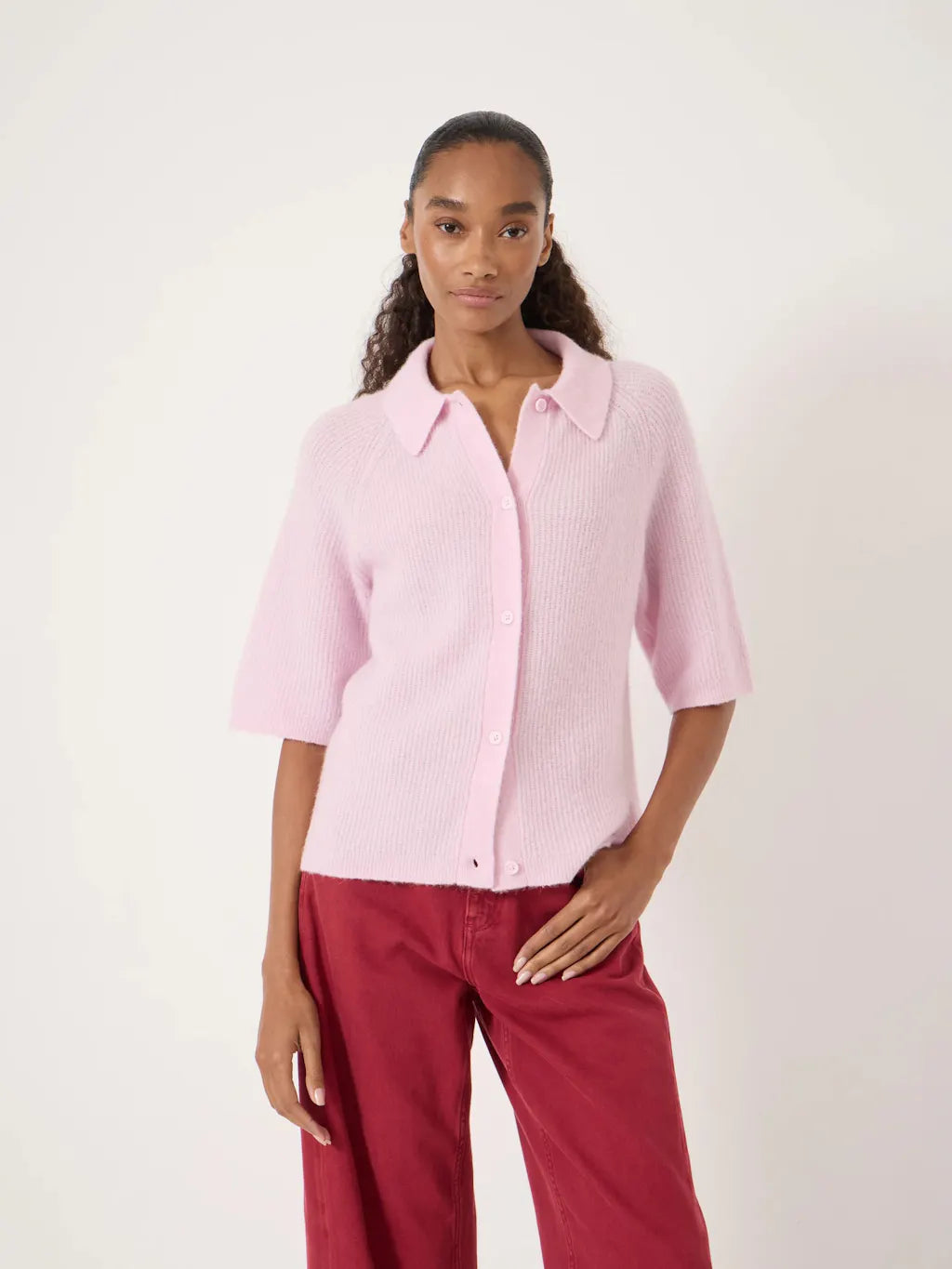 Light pink short-sleeve knitted cardigan with a collar, button front, and soft textured finish.