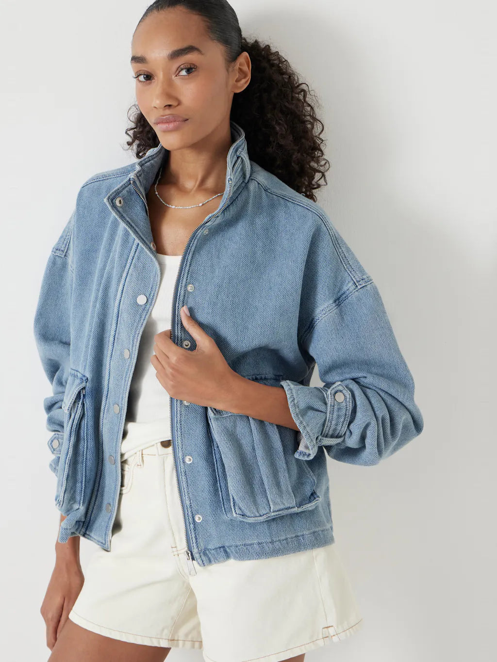 Soft blue denim jacket with high collar and zip.