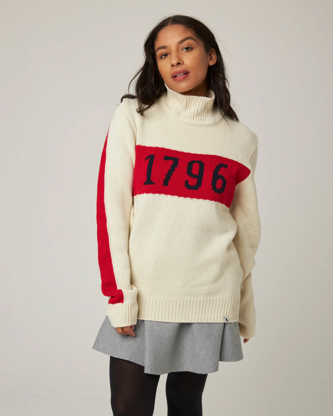 Model wearing cream ecru merino wool polo neck sweater with red stripe and '1796' knitted logo. Made by Peregrine Clothing and filtered for the Light Spring, Clear Spring, and Warm Spring colour seasons.