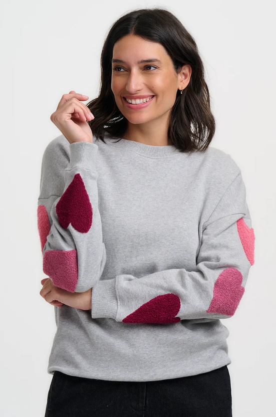Grey sweatshirt with pink boucle hearts on the sleeves.