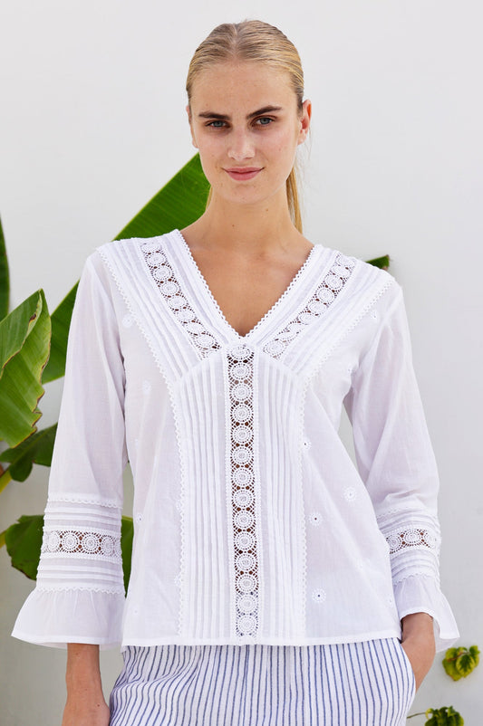 White cotton blouse with V-neckline, lace panel detailing, three-quarter sleeves, and fluted cuffs.