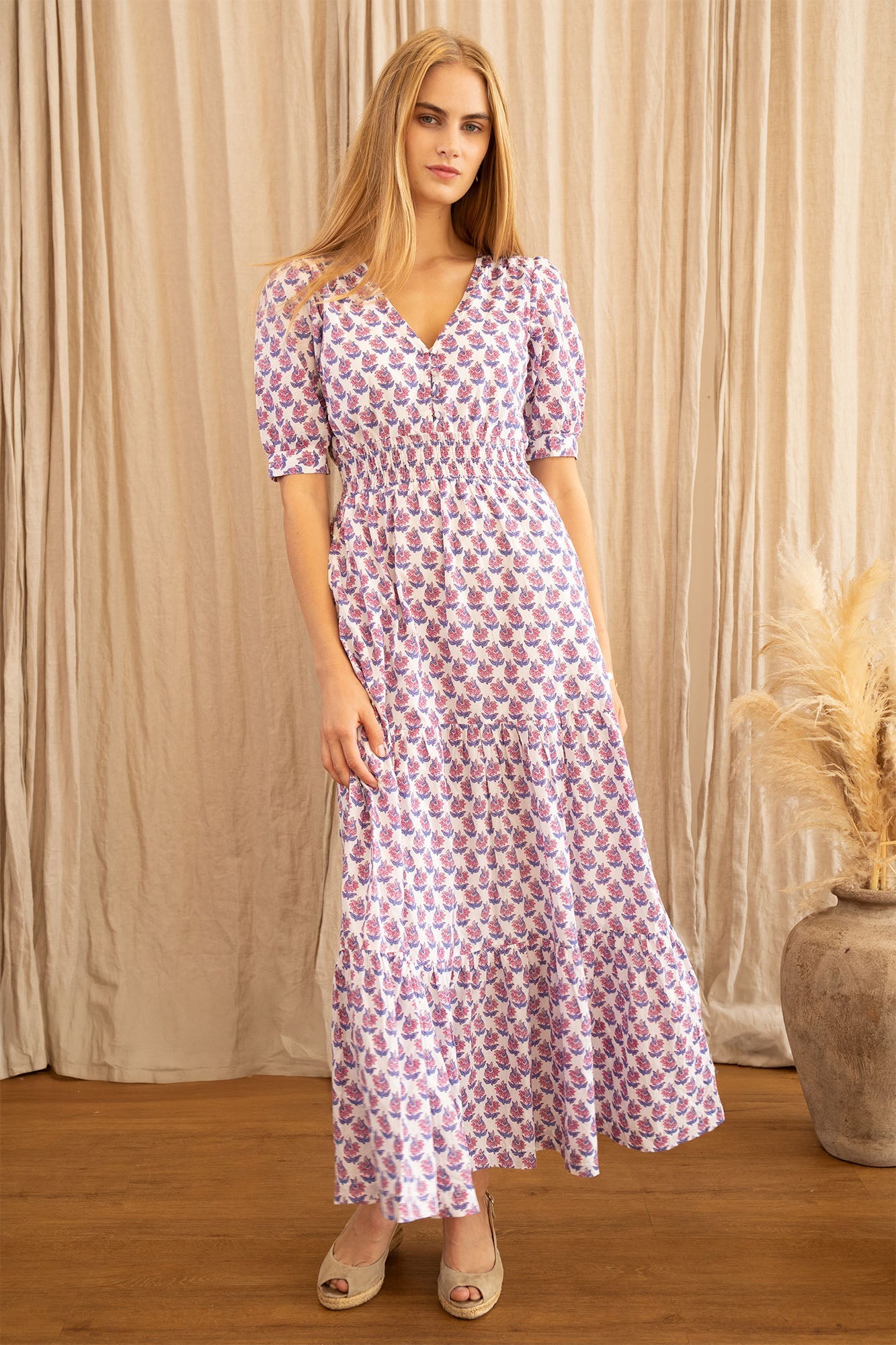 White midi dress with pink and blue floral print, V-neckline, short puff sleeves, and tiered skirt