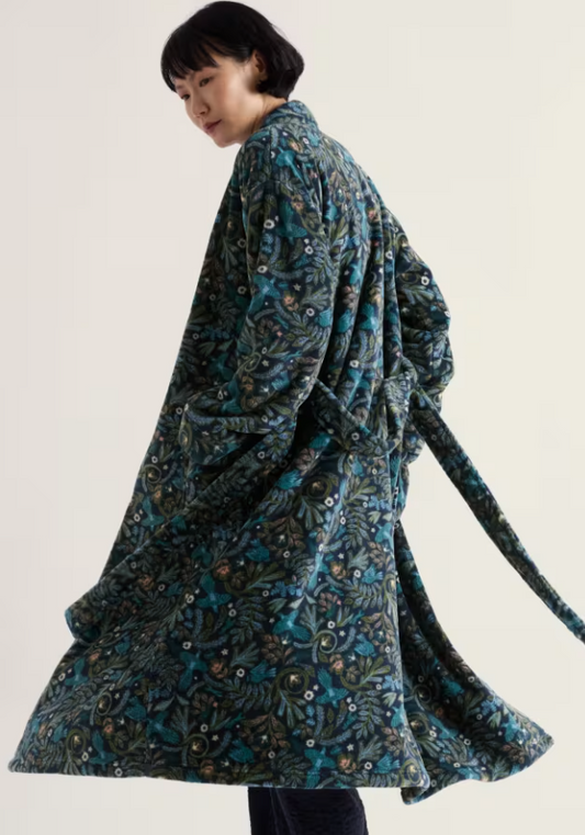 A model wearing a long-sleeved, belted robe with a dark teal and black botanical pattern, photographed against a solid off-white background.