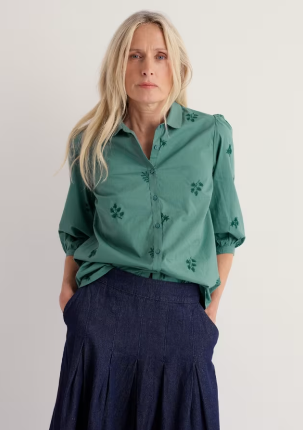 Teal blouse with green embroidered leaves.