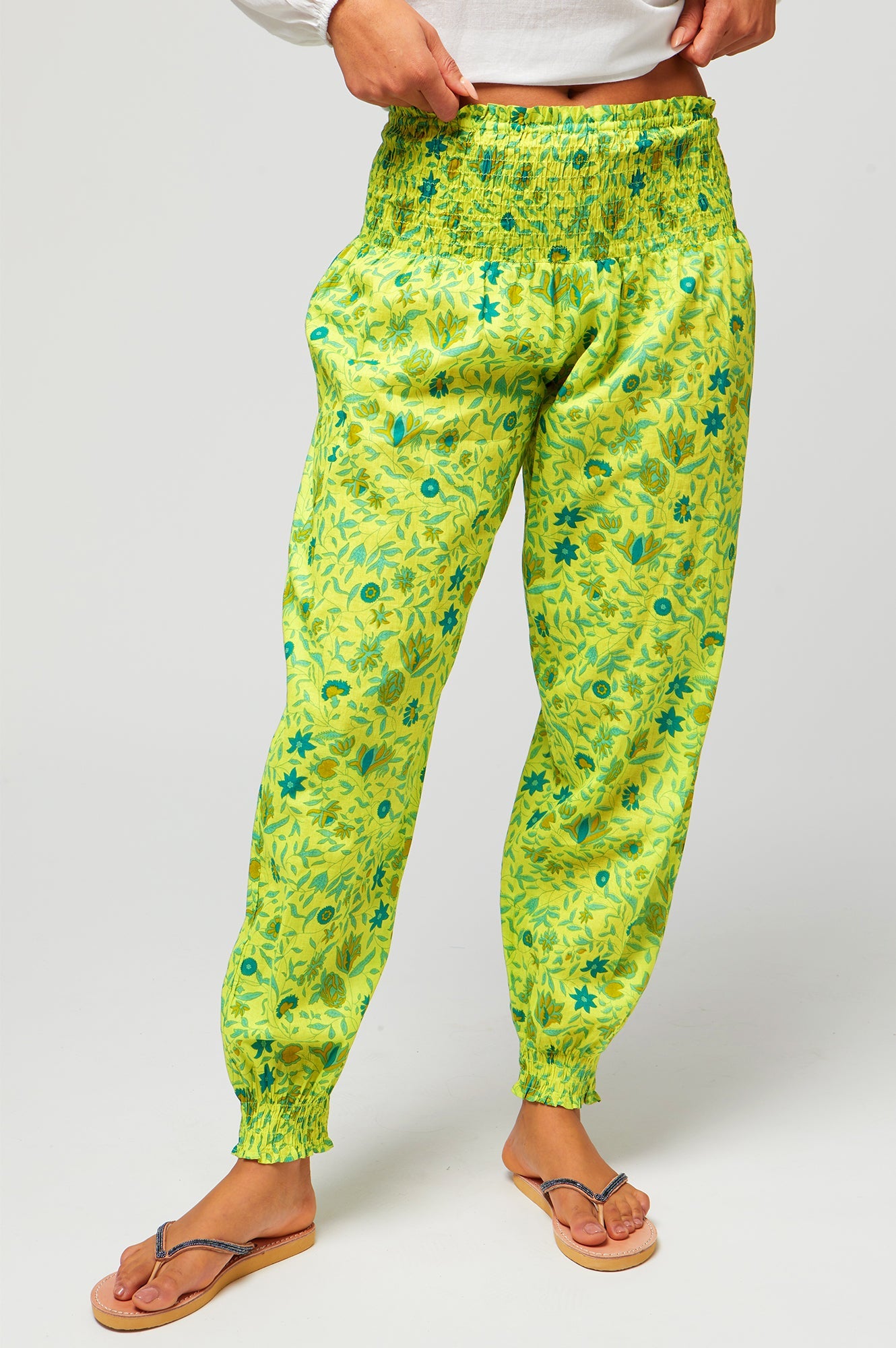 Lime green floral print trousers with elastic waistband, tapered leg, and cuffed ankles.