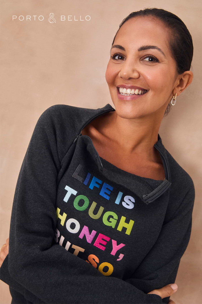 Charcoal zip-neck sweatshirt with bright multicoloured slogan text across the front.