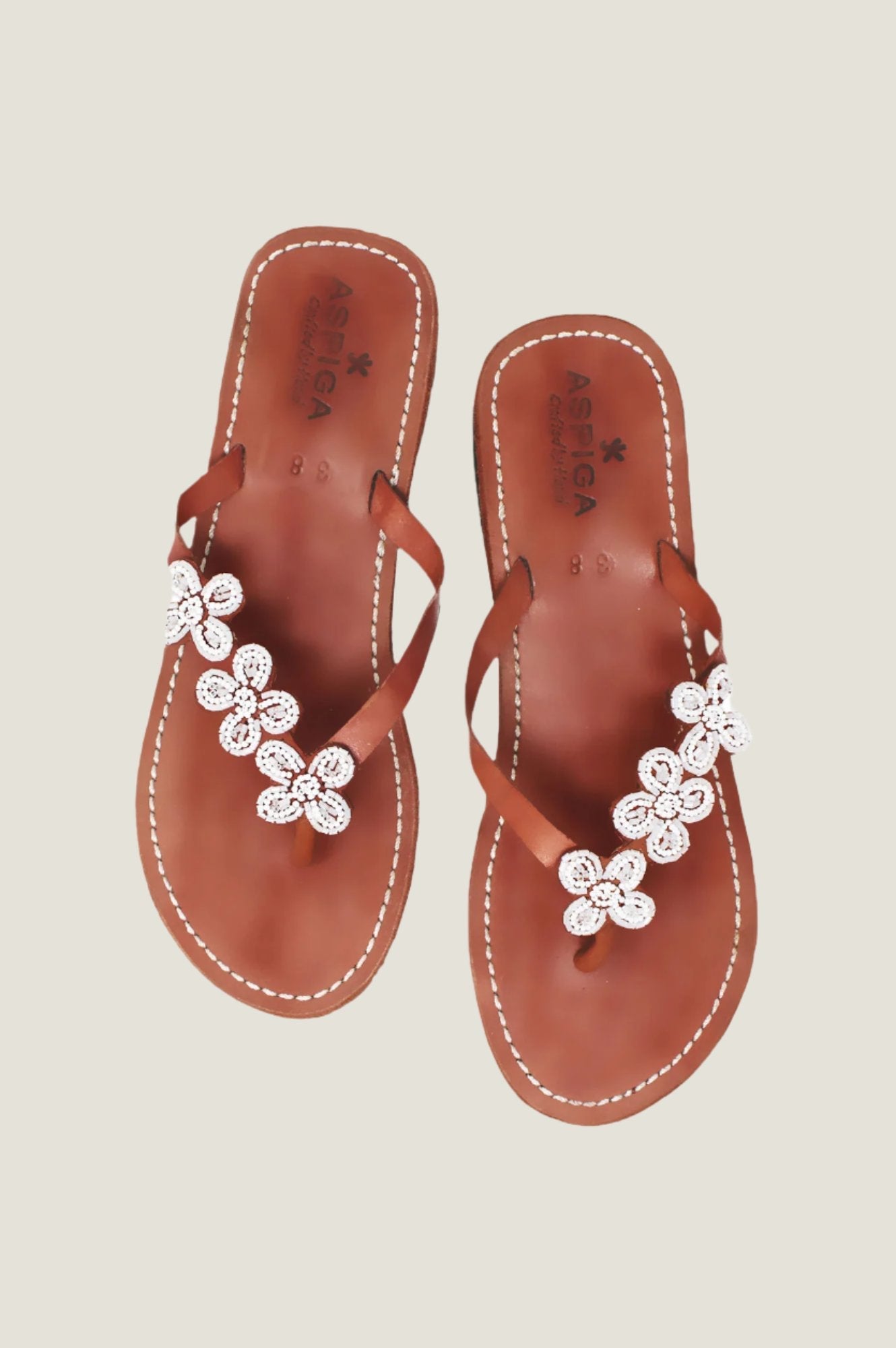 White beaded flower sandals with toe post, slim straps, and flat sole.