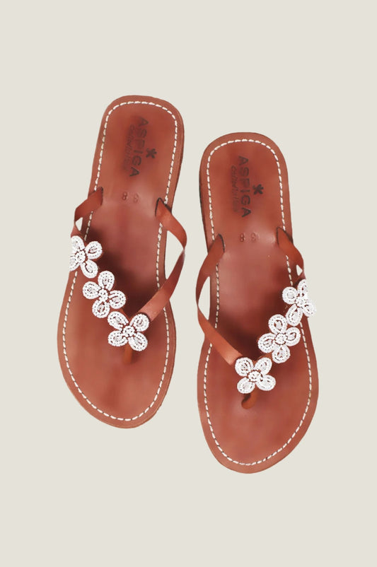White beaded flower sandals with toe post, slim straps, and flat sole.