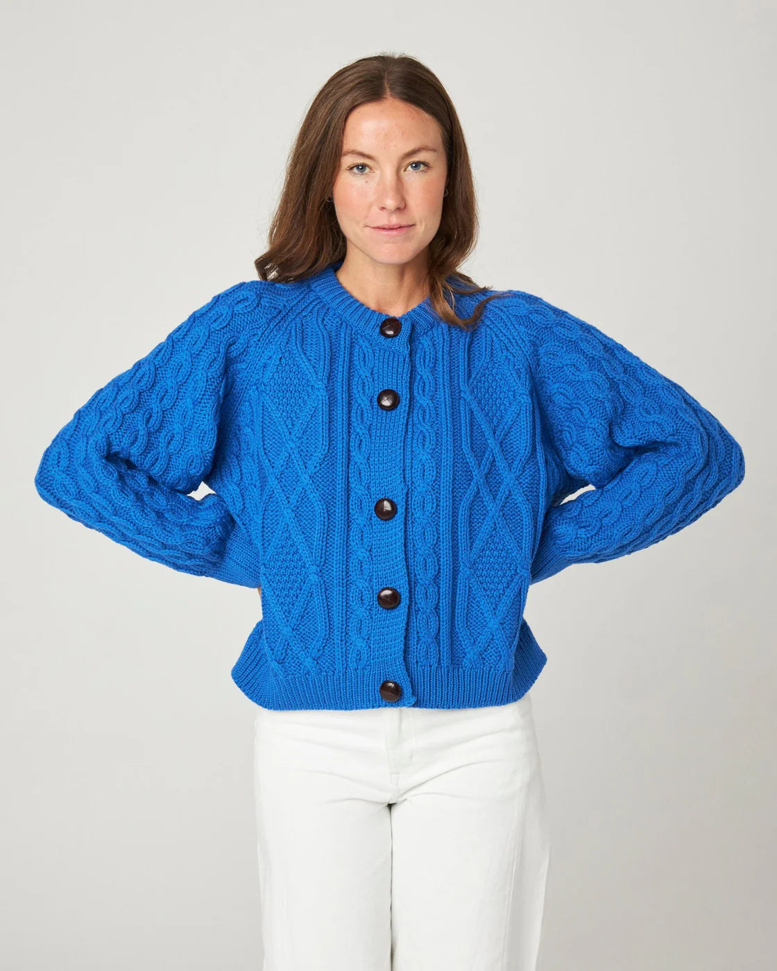 Model wears bright royal blue cable knit merino wool cardigan by Peregrine Clothing, filtered for the Clear Winter and Clear Spring colour seasons.