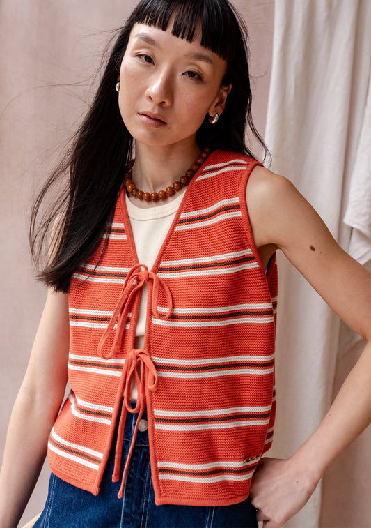 Coral orange striped knit sleeveless top with cream and brown stripes, tie-front fastening, and cropped fit