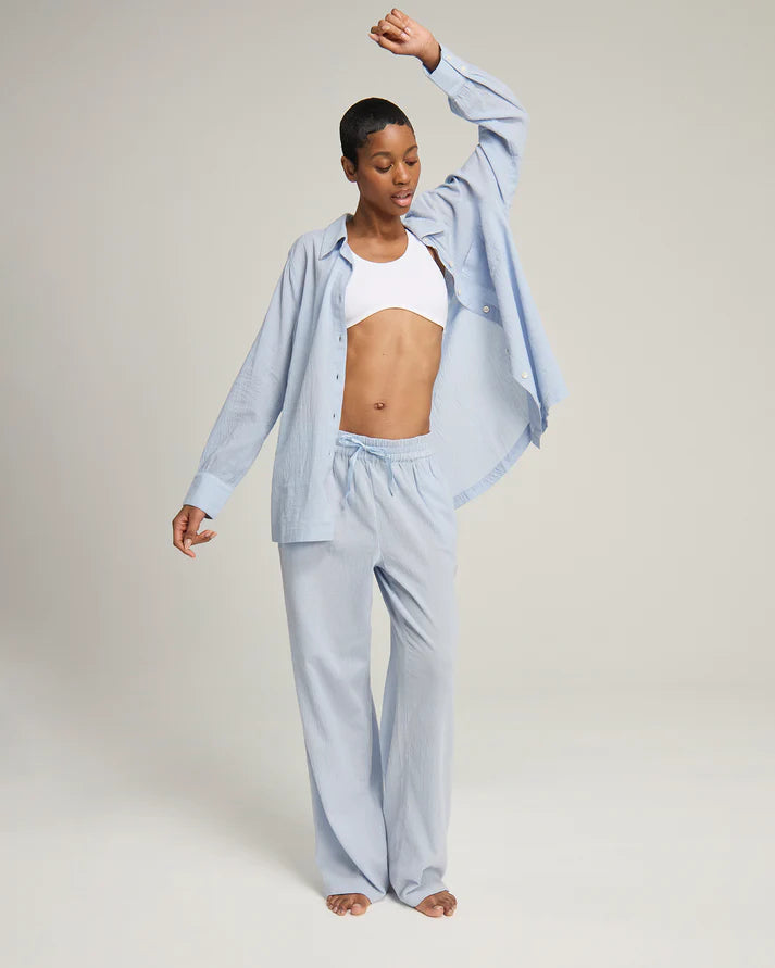 Woman wearing a 100% organic cotton light blue midi shirt pyjama top and trousers by Nudea, shown in a Light Summer and Cool Summer colour season palette, filtered by Shop My Palette.