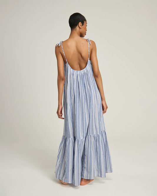 Back view of a woman wearing a blue and white striped organic cotton nightdress on a plain background. The Trapeze Dress from Nudea is filtered for the Soft Summer, Light Summer, and Cool Summer colour seasons by Shop My Palette.