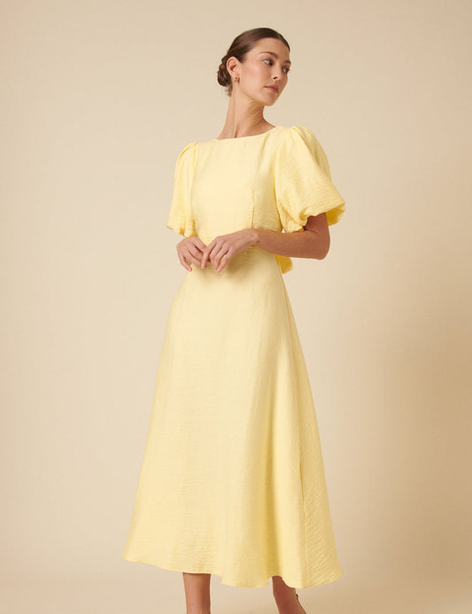 Butter yellow round neck midi dress with puff sleeves and bow tie at back.