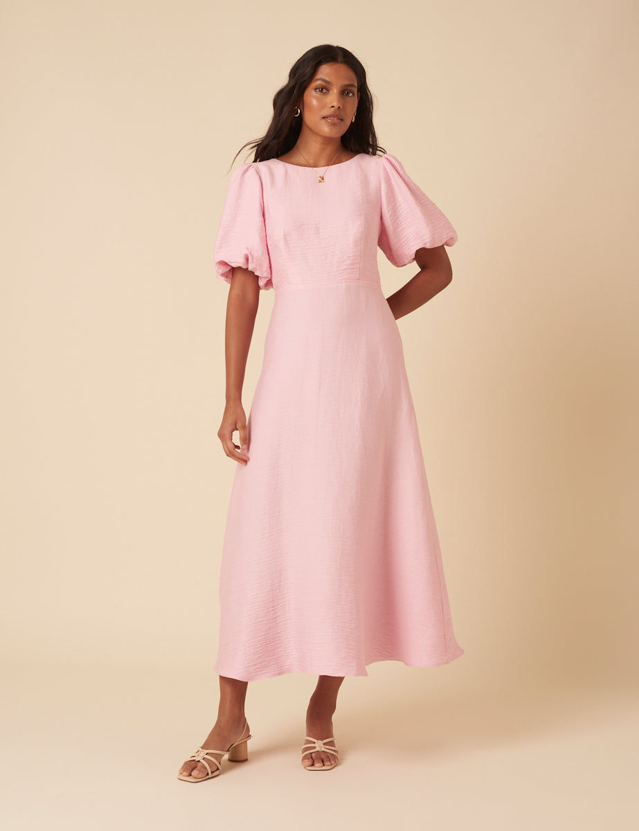 Baby pink round neck midi dress with puff sleeves and bow tie back.