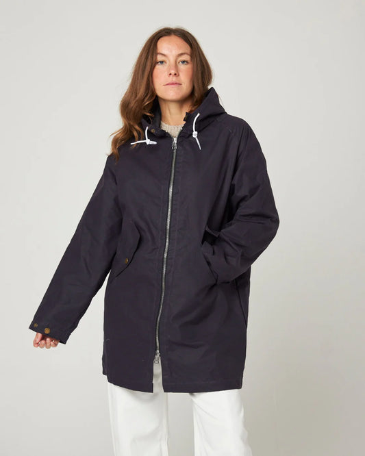 Model wears a dark navy waxed cotton cagoule with a silver zip, made by Peregrine Clothing and filtered for the Deep Winter, Clear Winter, and Cool Winter colour seasons by Shop My Palette.