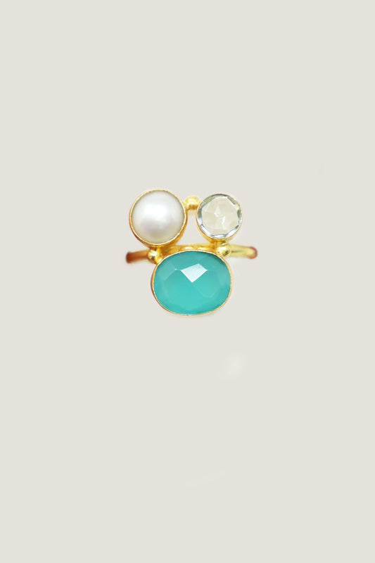 Gold ring with turquoise oval stone, pearl accent, and clear faceted crystal detail.