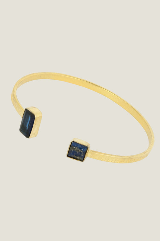 Gold cuff bracelet with two rectangular dark blue lapis lazuli stone details.