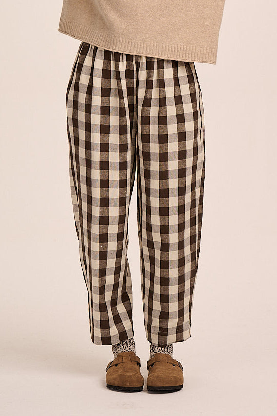 Brown and cream check trousers with elasticated waist, tapered leg silhouette, and lightweight woven fabric.
