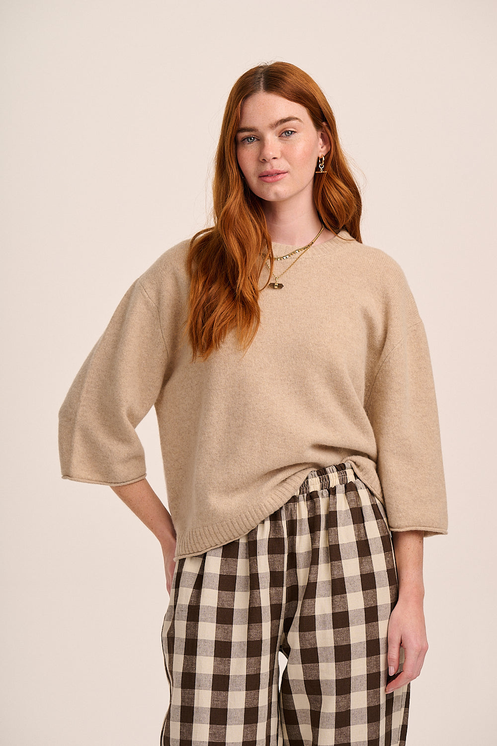 Beige knitted top with round neckline, three-quarter length sleeves, and relaxed boxy silhouette.