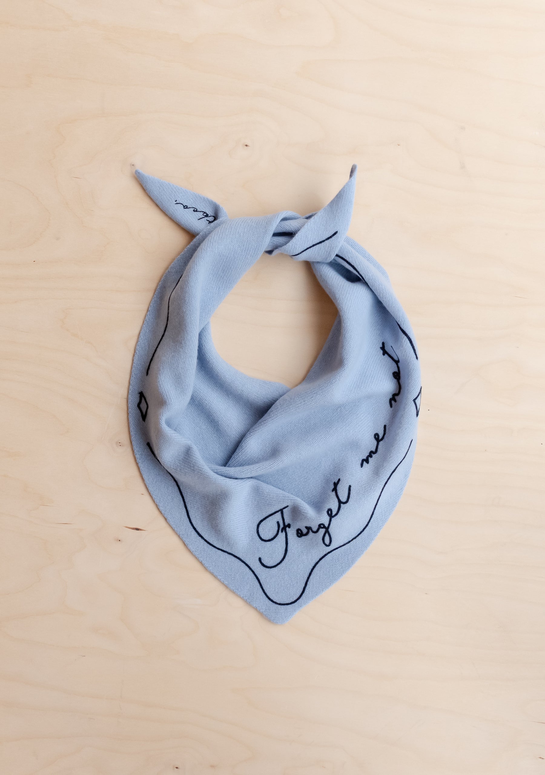 Light blue merino wool neck scarf with black line detailing and handwritten-style text, triangular shape