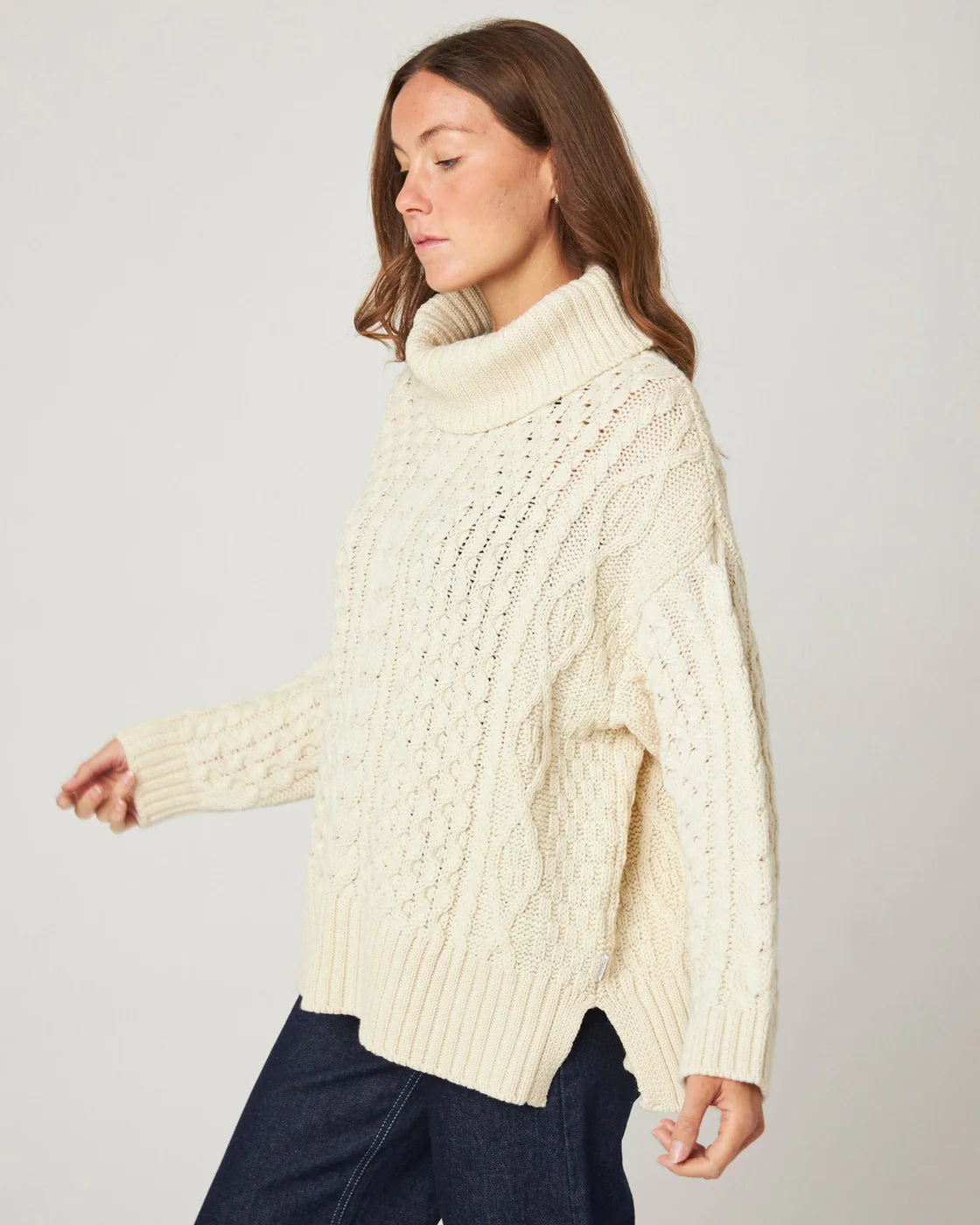 Model wears a cream ecru cable knit polo neck sweater, from Peregrine Clothing, filtered for the Warm Spring, Clear Spring, and Light Spring colour seasons.