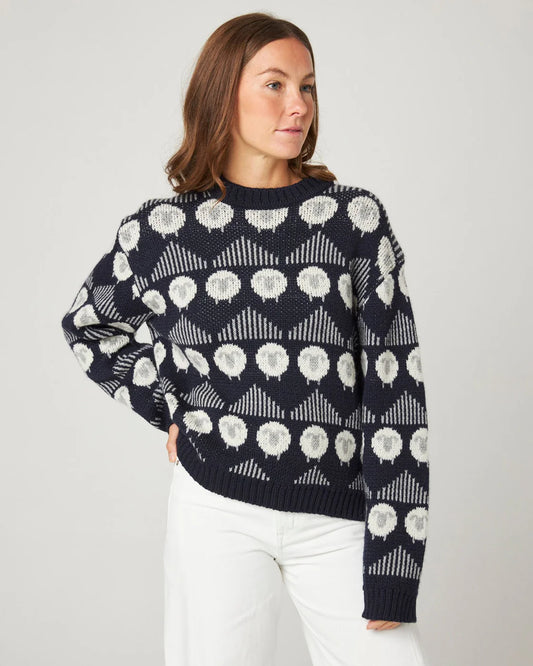 Model wearing a navy merino wool sweater with a sheep pattern by Peregrine Clothing, shown in a Deep Winter / Cool Winter-friendly colour.