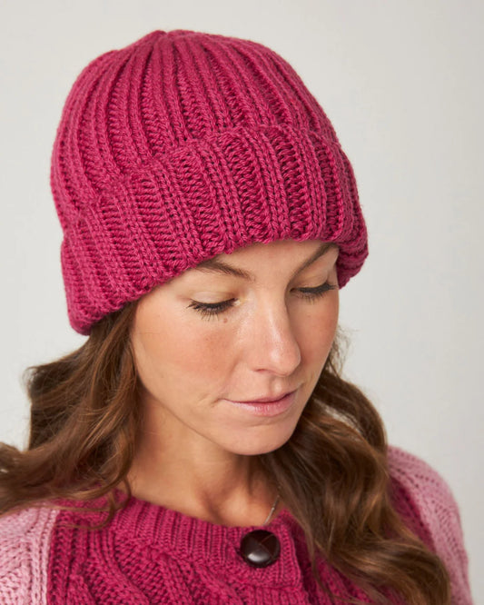 Model wears a clear fuchsia pink knitted merino wool beanie hat by Peregrine Clothing, filtered for Deep Winter, Clear Winter, and Cool Winter by Shop My Palette.