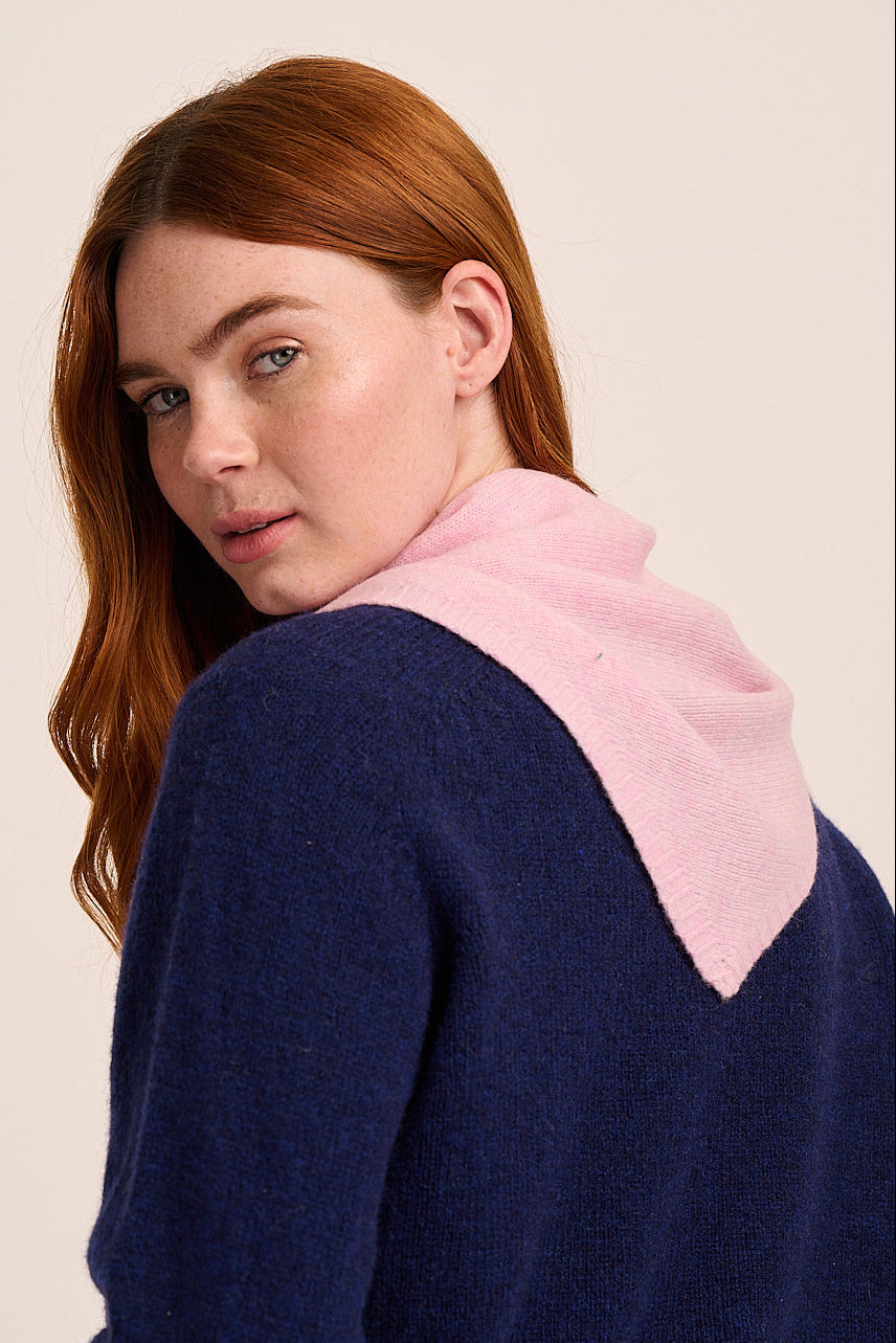 Light pink knitted scarf with soft texture and triangular drape.