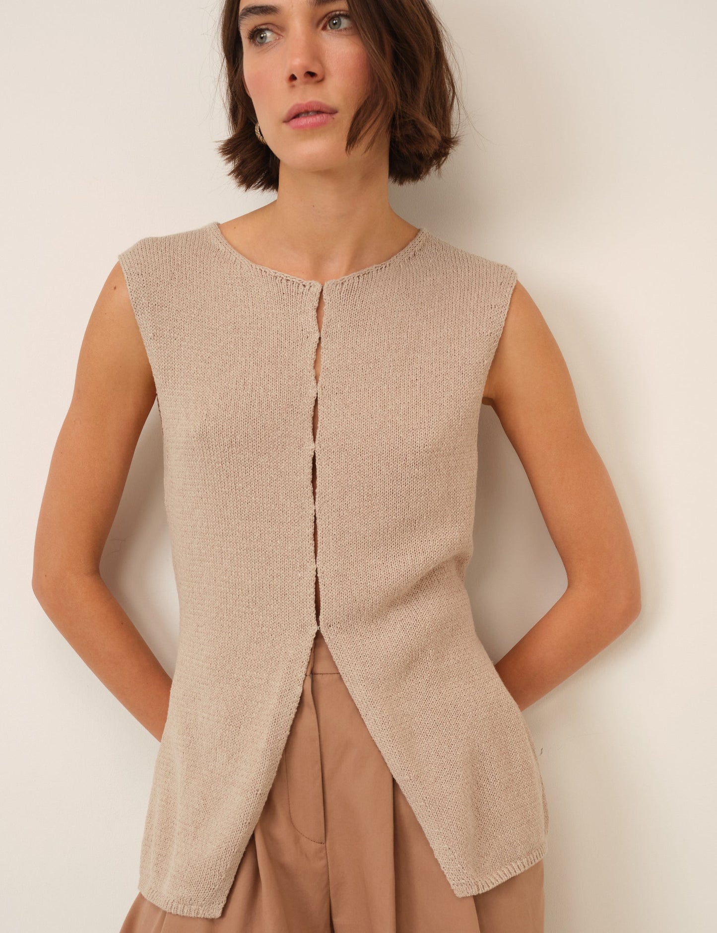 Sand coloured knitted sleeveless long-line cardigan.