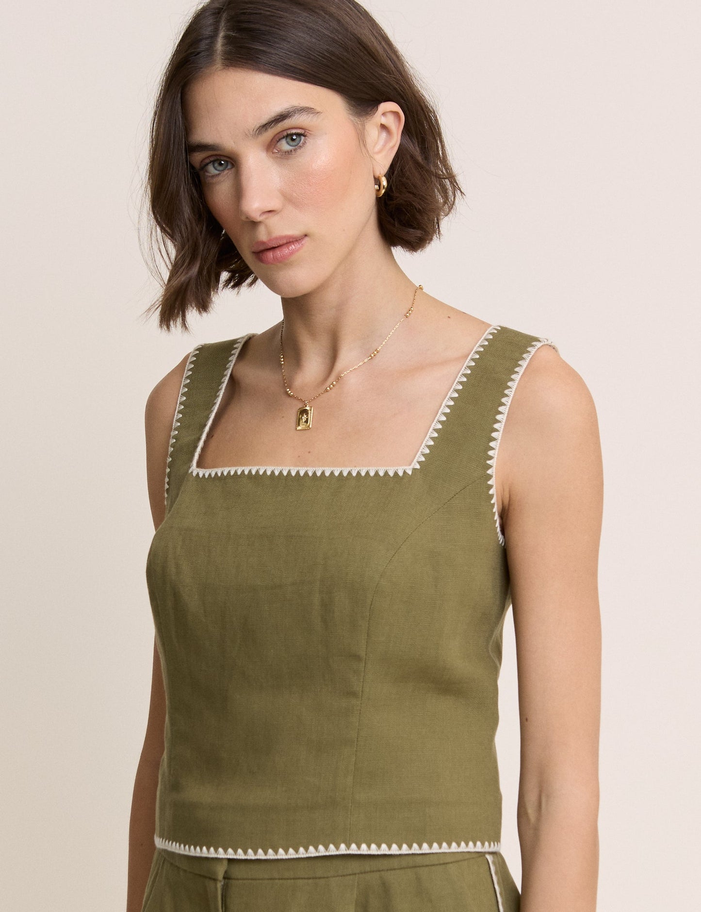 Olive green tailored top with stitched edges.