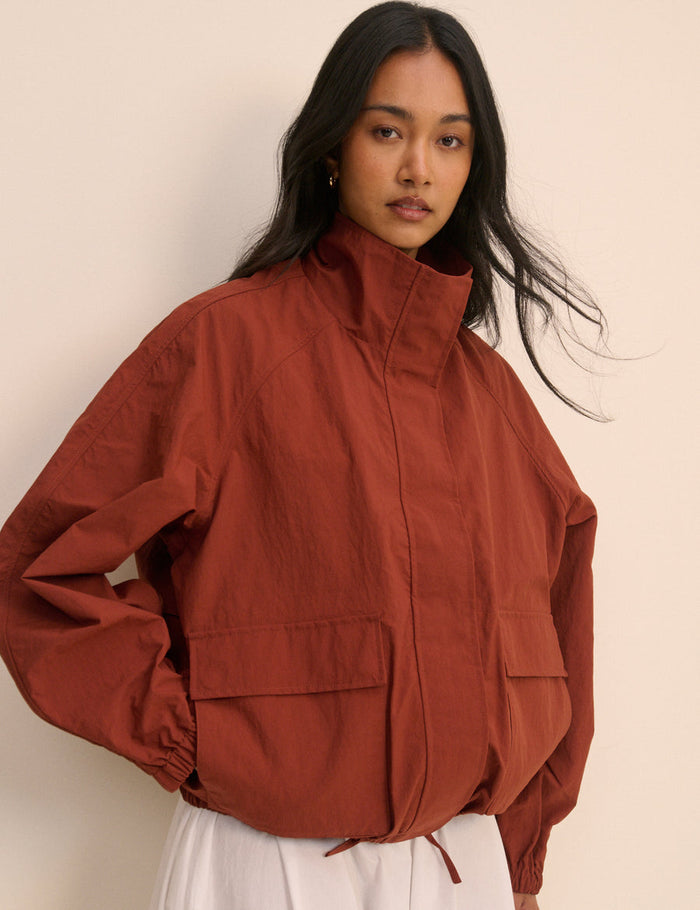 Person wearing a rust jacket against a plain background