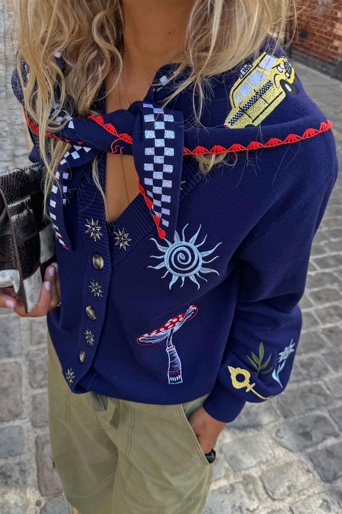 Navy knitted scarf with bright embroidered details and red trim.