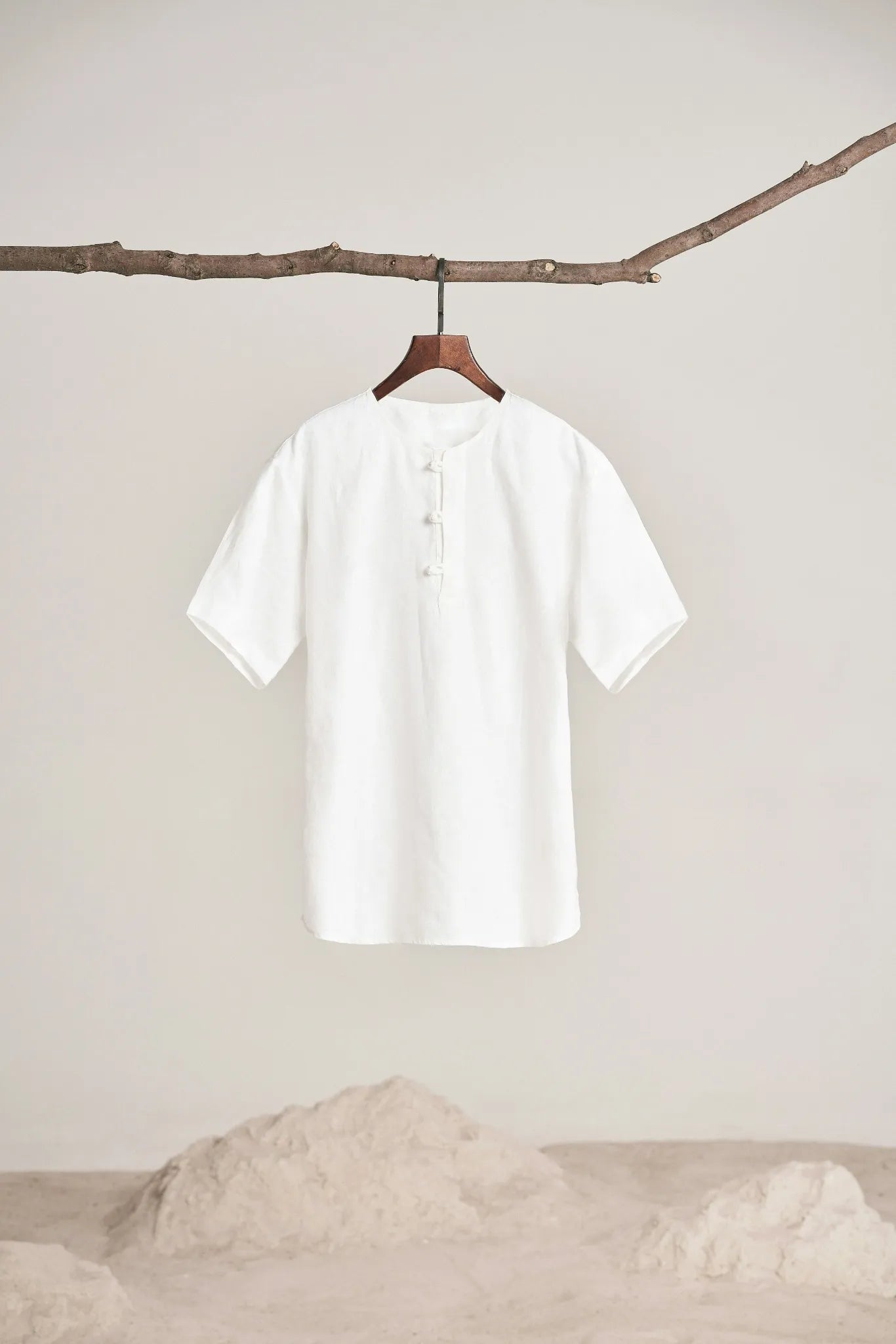 White shirt hanging on a branch against a plain background