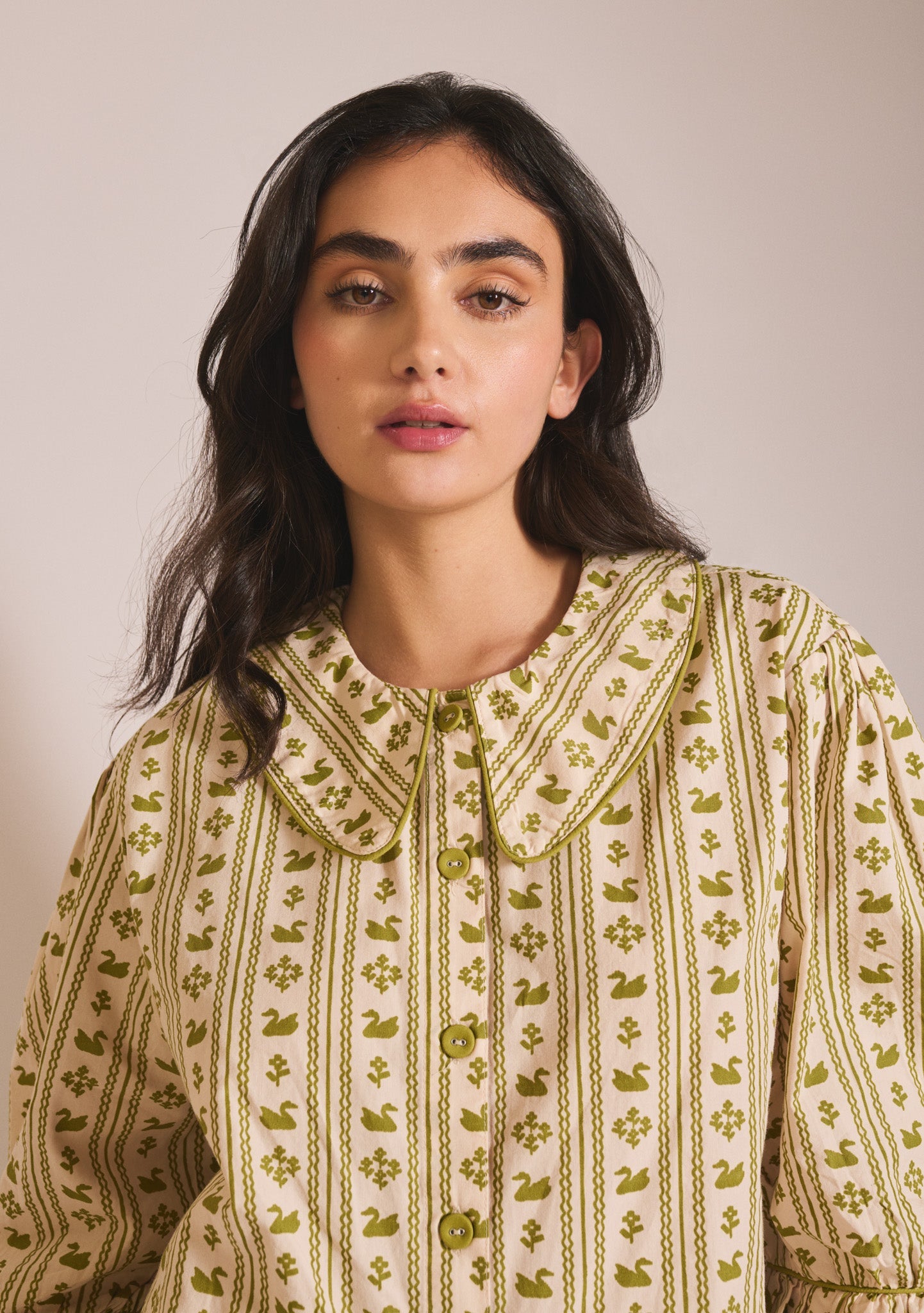 Olive green and cream patterned long-sleeve pyjama set with Peter Pan collar and swan pattern.