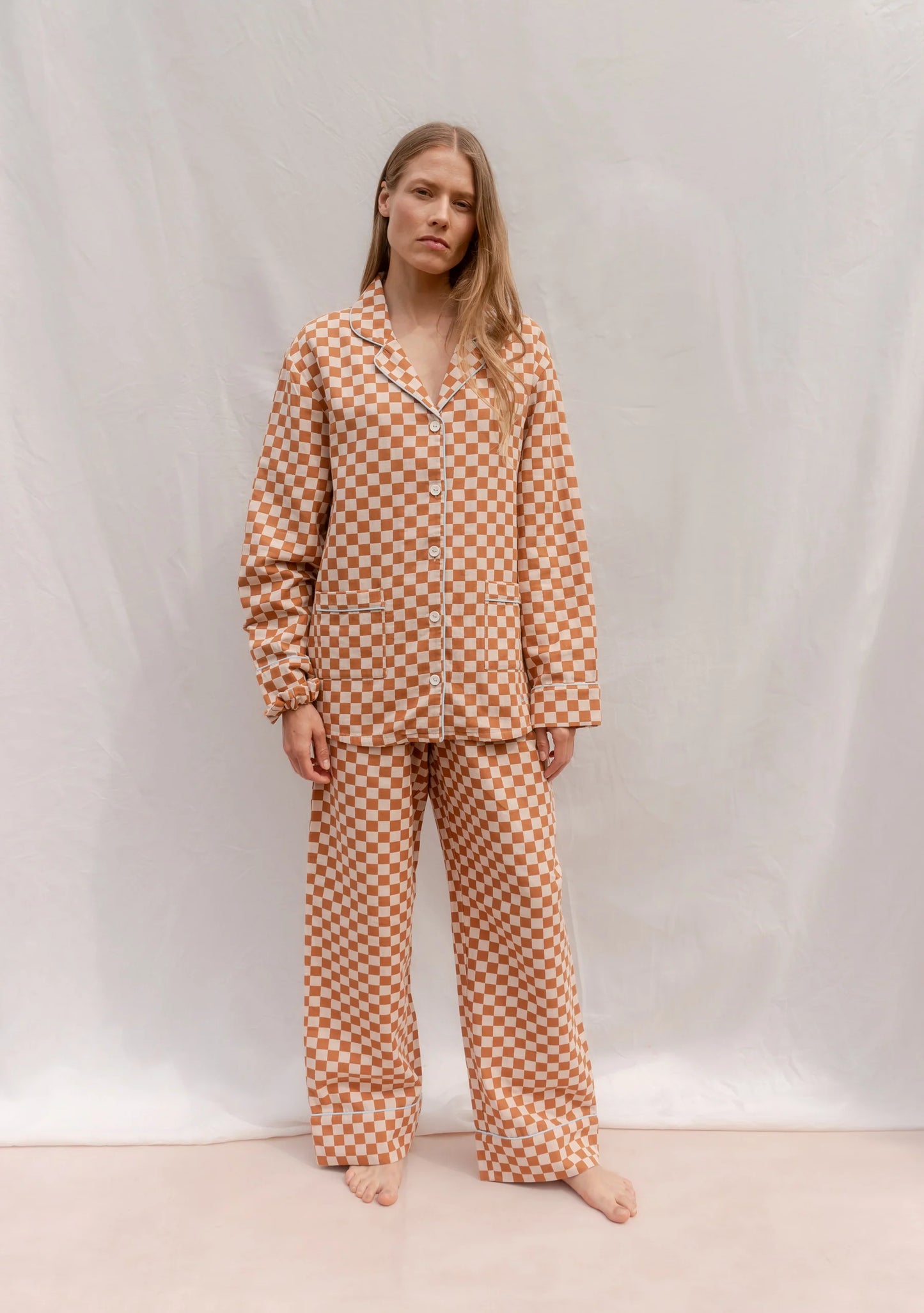 Person wearing an orange and cream checkered pyjama set against a plain background. Pyjamas are by TBCo and are filtered by Shop My Palette for the Light Spring, Warm Spring, Warm Autumn, and Soft Autumn colour seasons.