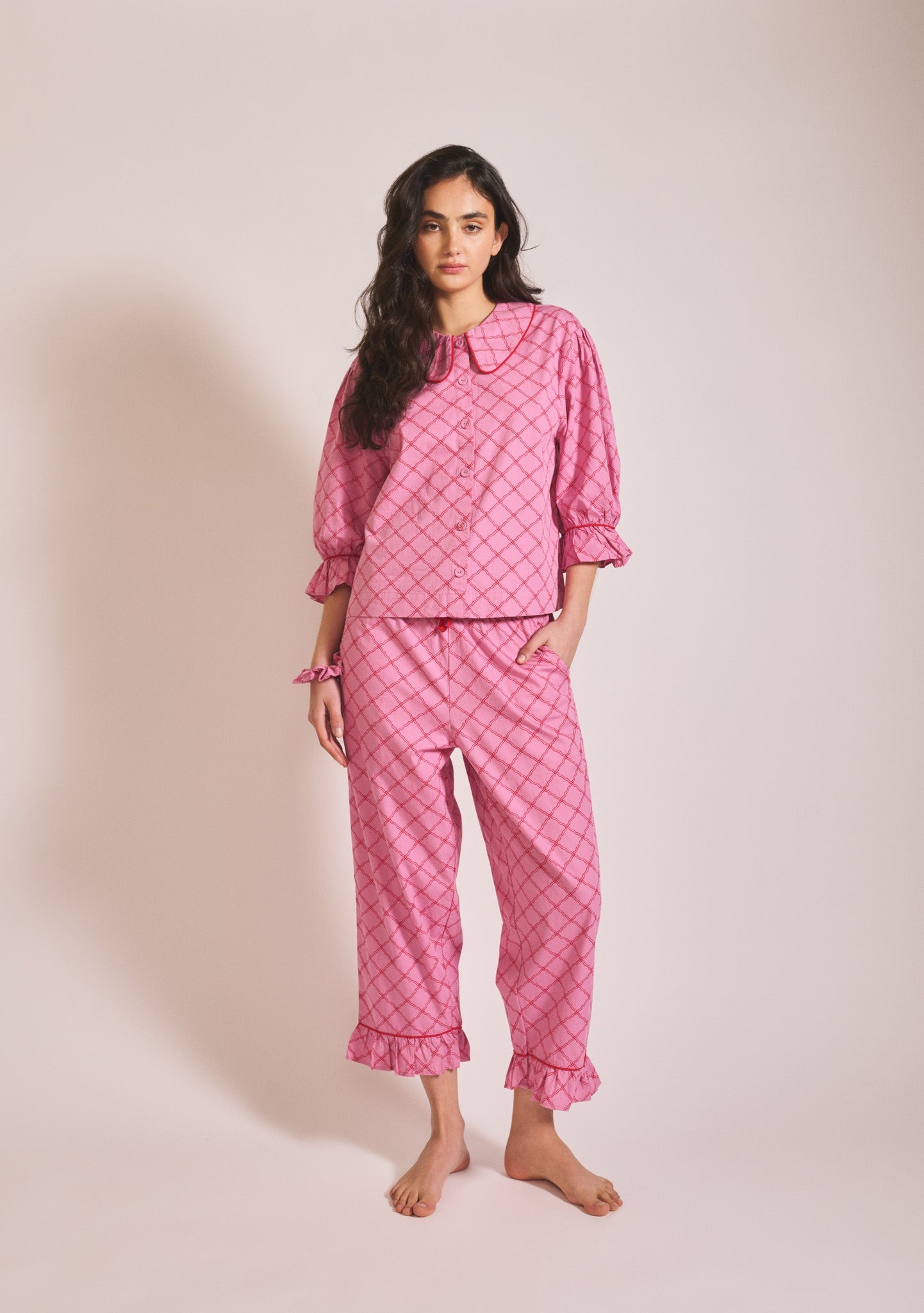 Pink patterned long-sleeve pyjama set with button-up top, Peter Pan collar, and matching trousers.