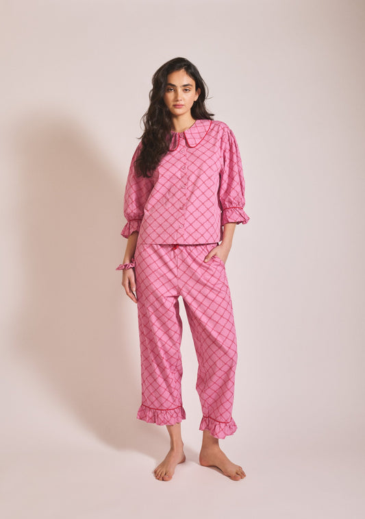 Pink patterned long-sleeve pyjama set with button-up top, Peter Pan collar, and matching trousers.
