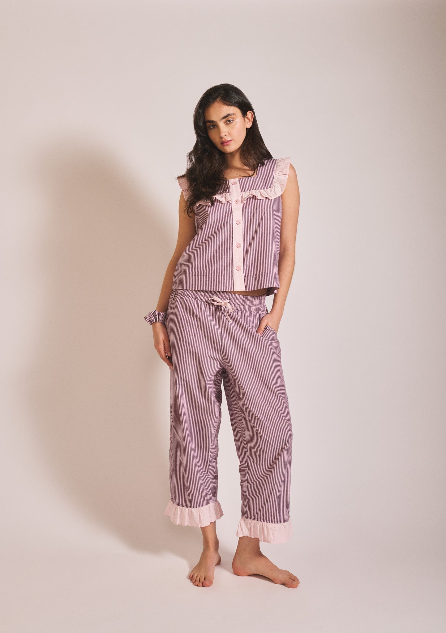 Muted mauve pink and burgundy striped sleeveless pyjama set with ruffle trim and matching cropped trousers.